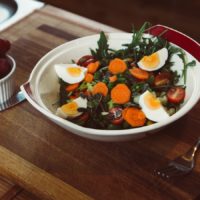 Un plat de salades avec des oeufs et des raisins.